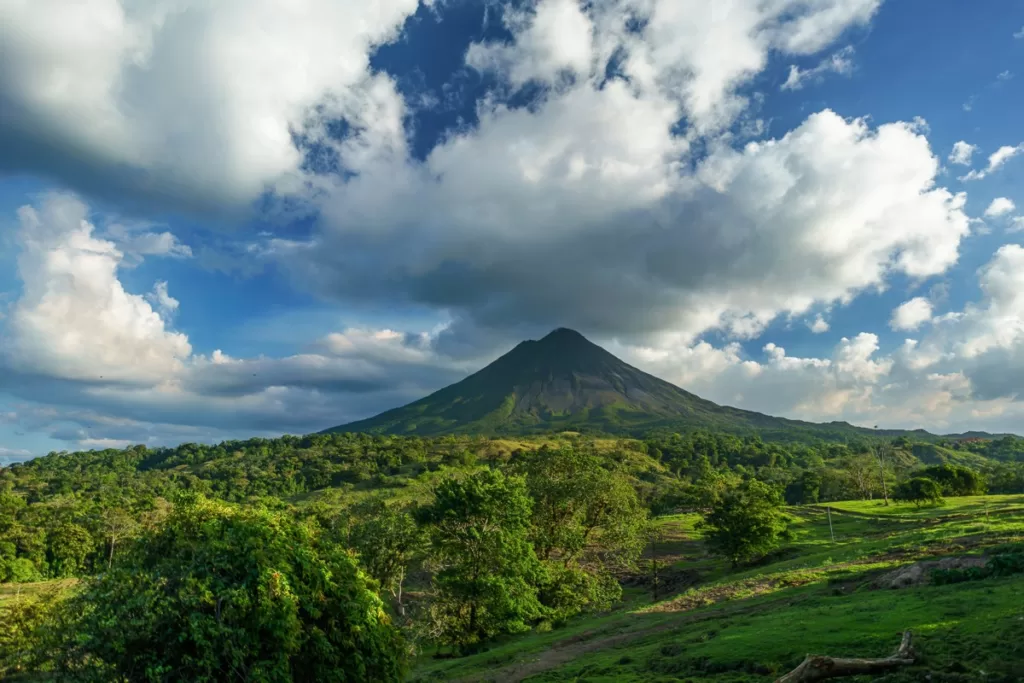 A stunning view of the iconic volcano in Costa Rica, surrounded by lush greenery and a clear blue sky.
